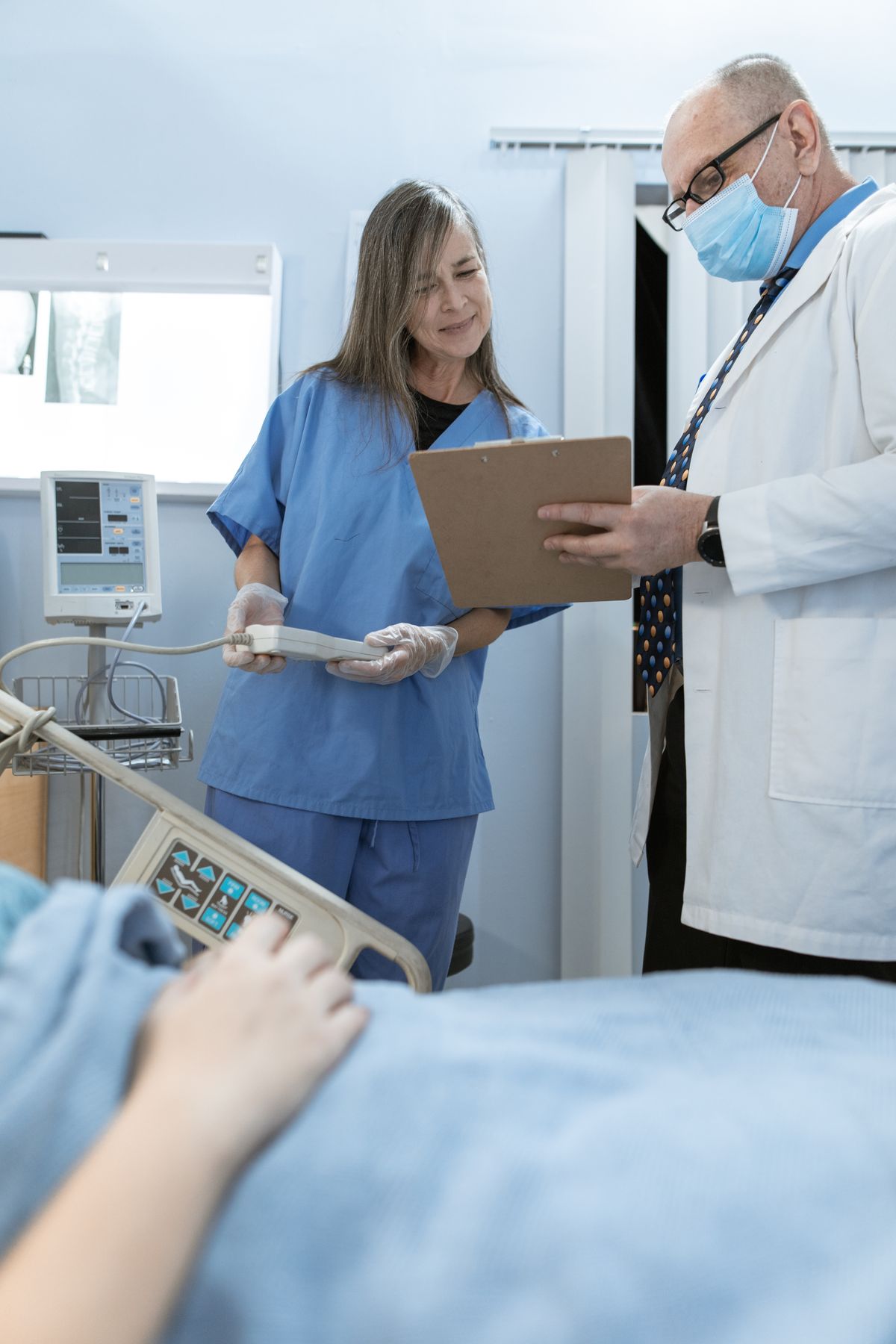 A nurse and a doctor reviewing a patient's chart at the bedside